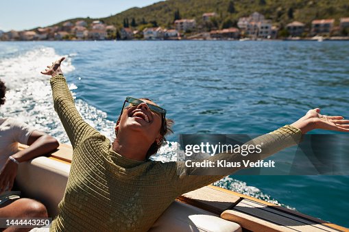 Happy woman with arms raised in motorboat Happy woman with arms raised in motorboat