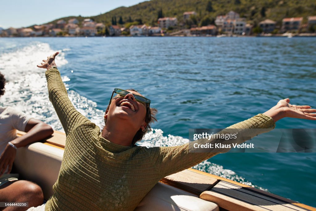 Happy woman with arms raised in motorboat