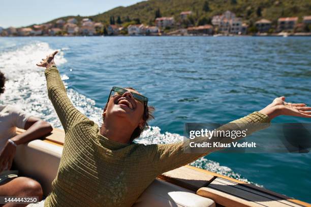 happy woman with arms raised in motorboat - summer woman stock pictures, royalty-free photos & images