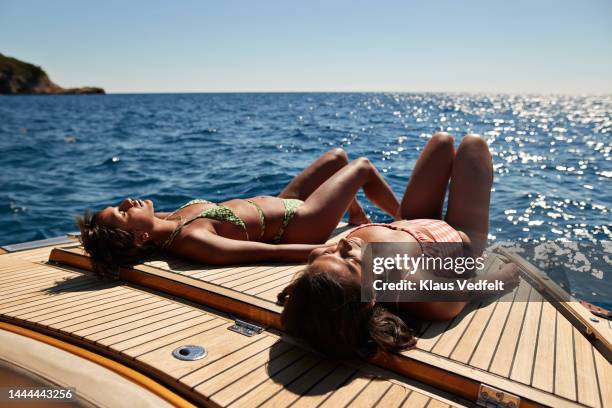 young female friends sunbathing on boat deck - só mulheres jovens - fotografias e filmes do acervo