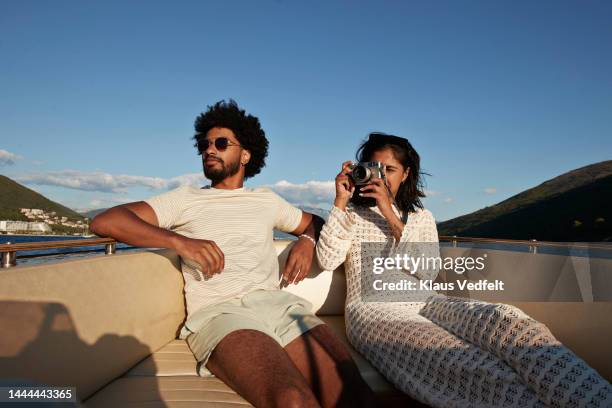 young woman photographing on camera by boyfriend - calções azuis imagens e fotografias de stock