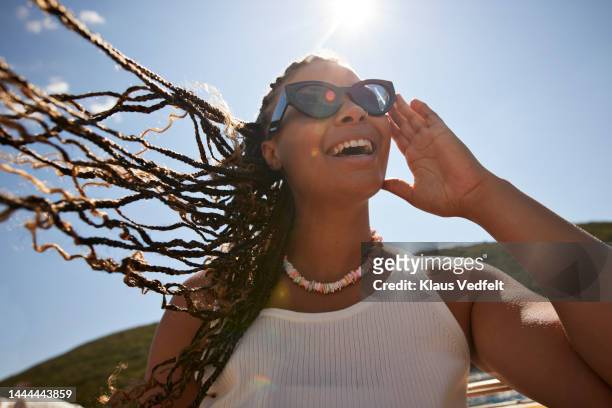 happy woman adjusting sunglasses on sunny day - travel stock-fotos und bilder