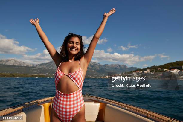 happy young woman with arms raised in boat - baño-de-pies fotografías e imágenes de stock