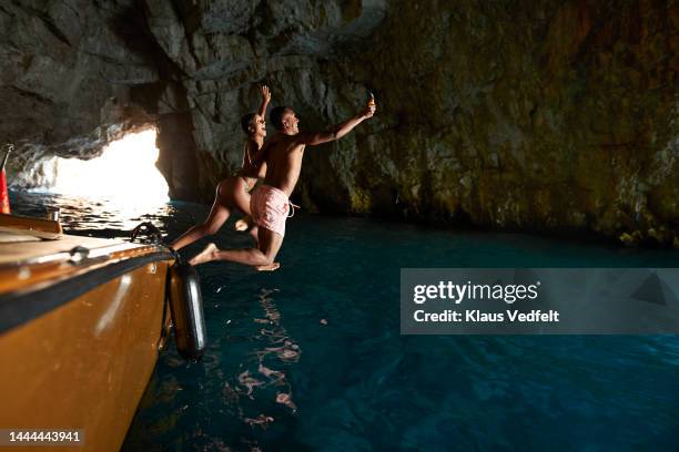 cheerful couple filming while jumping in sea - montenegro stock-fotos und bilder