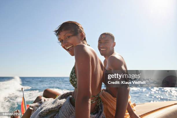 happy young couple sitting on boat deck - blue shorts stock-fotos und bilder