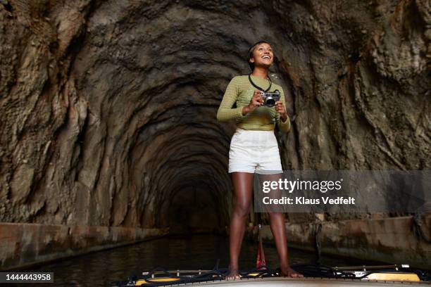 excited woman with camera standing in cave - camera boat stock pictures, royalty-free photos & images