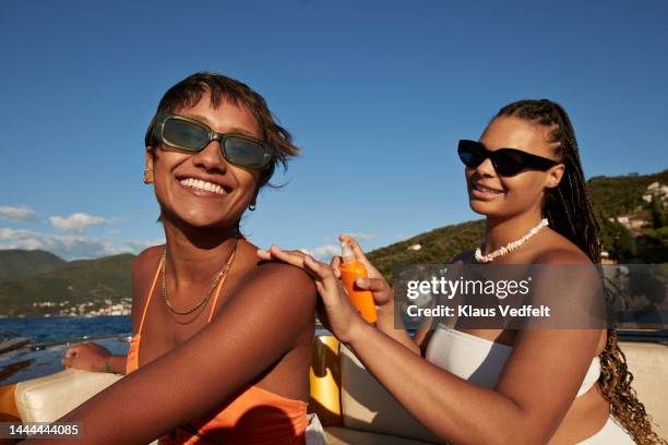 woman applying sunscreen on friend's shoulder - proteção uv - fotografias e filmes do acervo