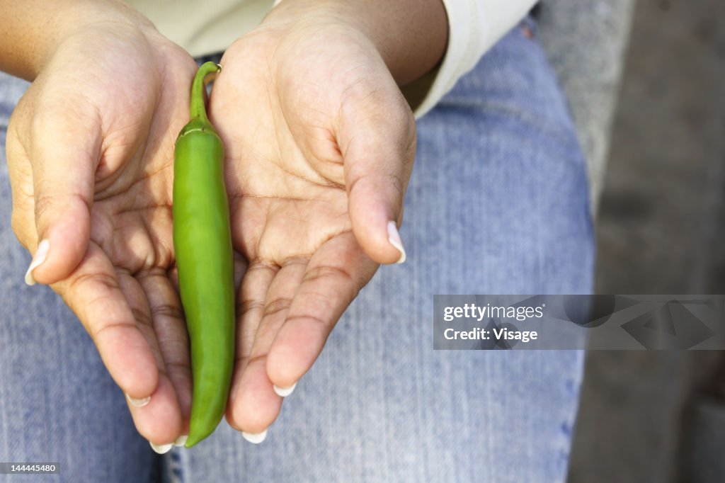 Close up of hands holding green chili