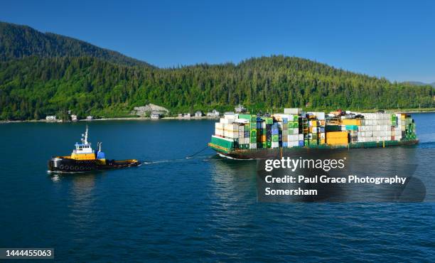 tug pulls barge laden with goods - alaska location stock-fotos und bilder