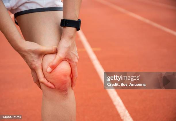 close up of female runner holding her knee while having suffering from knee pain after running. - sehnenscheidenentzündung stock-fotos und bilder