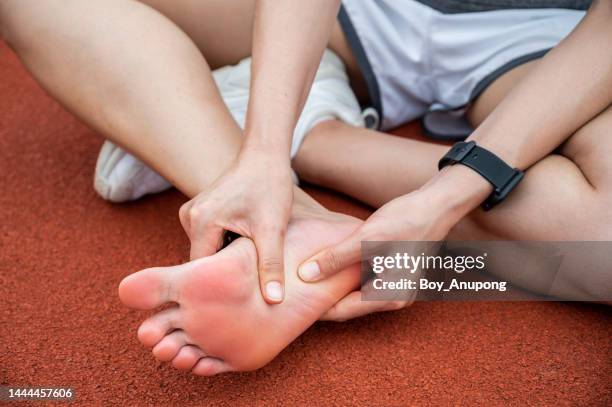 cropped shot view of female runner suffering from injury and she trying to do foot massage by herself. - soles pose stock pictures, royalty-free photos & images