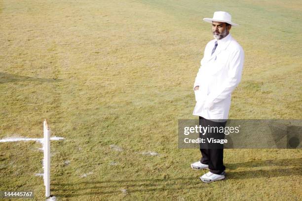 umpire standing before the stumps - cricket umpire stock pictures, royalty-free photos & images