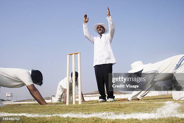 fielders bowing their heads before the umpire - cricket umpire stock-fotos und bilder