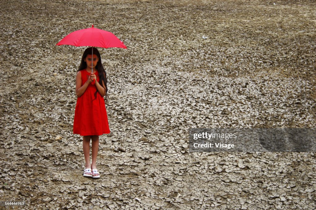 A girl with an umbrella on a dry land