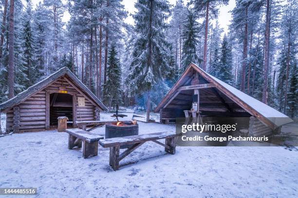 wooden shelter hut and a fire in the forest during winter with snow - fireplace forest stock pictures, royalty-free photos & images