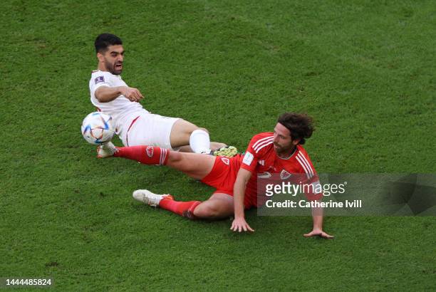 Joe Allen of Wales tackles Ali Karimi of IR Iran during the FIFA World Cup Qatar 2022 Group B match between Wales and IR Iran at Ahmad Bin Ali...