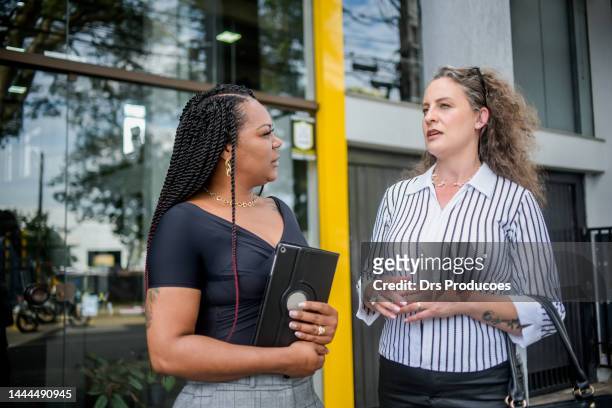 businesswomen talking in front of work - gerente stockfoto's en -beelden