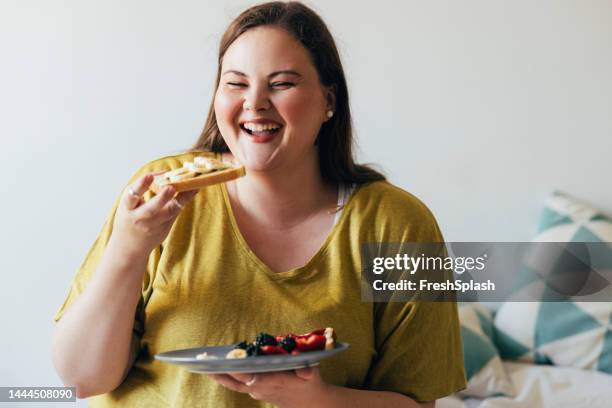 plus size woman enjoying her breakfast - fat nutrient 個照片及圖片檔