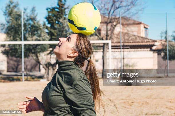 woman controlling the ball with her head. ground soccer field. female soccer concept. - ballon de football - fotografias e filmes do acervo