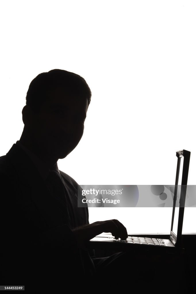 Silhouette of a businessman using a laptop