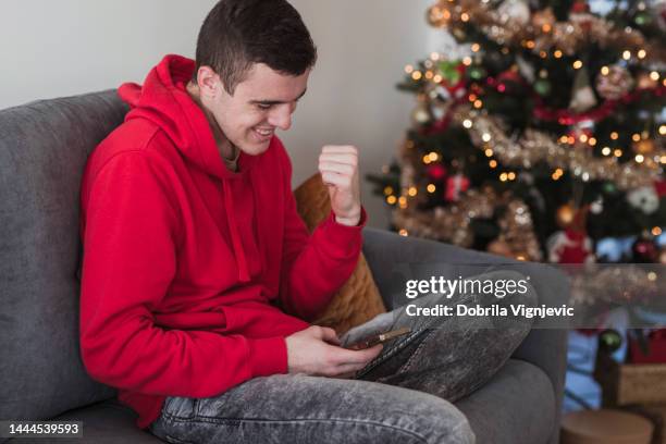 happy man gesturing when surfing the net after online betting on football - good news stock pictures, royalty-free photos & images