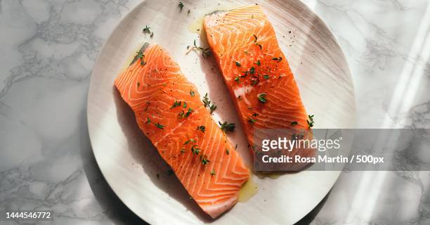 high angle view of salmon slice with herbs on plate on table,egypt - salmon steak stockfoto's en -beelden