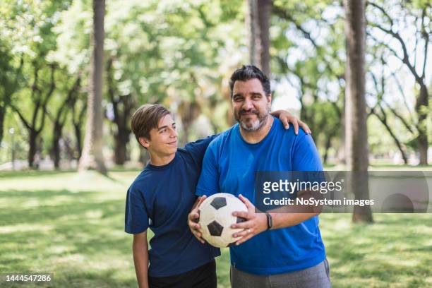 father and son playing soccer in the park - father and son park stock pictures, royalty-free photos & images