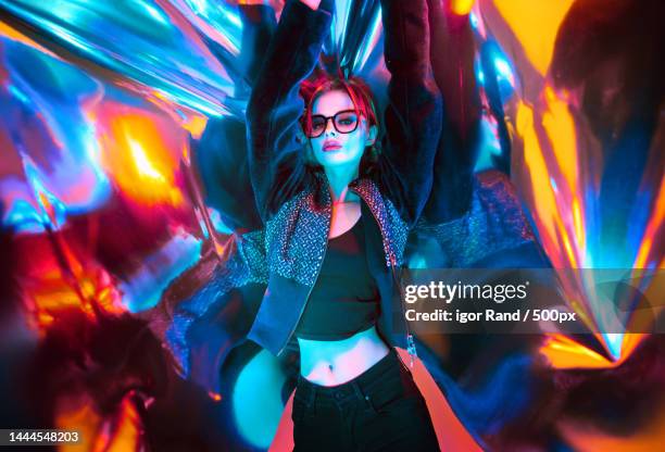 beautiful woman with eyeglasses standing against colored plastic wrap with neon lights,china - editorial 個照片及圖片檔