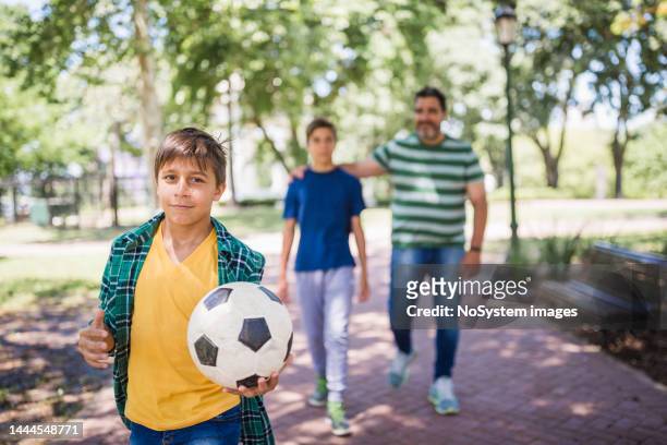 father and two sons playing soccer in the park - movinglove 15, 2019 stock pictures, royalty-free photos & images
