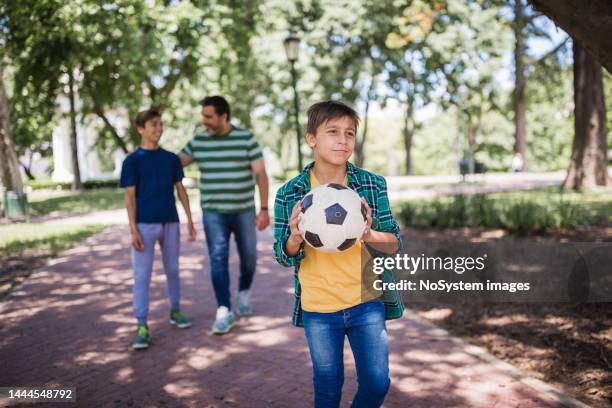 father and two sons playing soccer in the park - movinglove 15, 2019 stock pictures, royalty-free photos & images