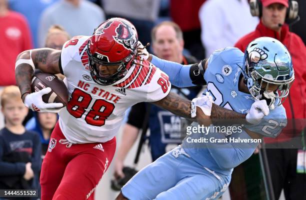 Devin Carter of the North Carolina State Wolfpack stiff-arms Giovanni Biggers of the North Carolina Tar Heels during the first half of their game at...