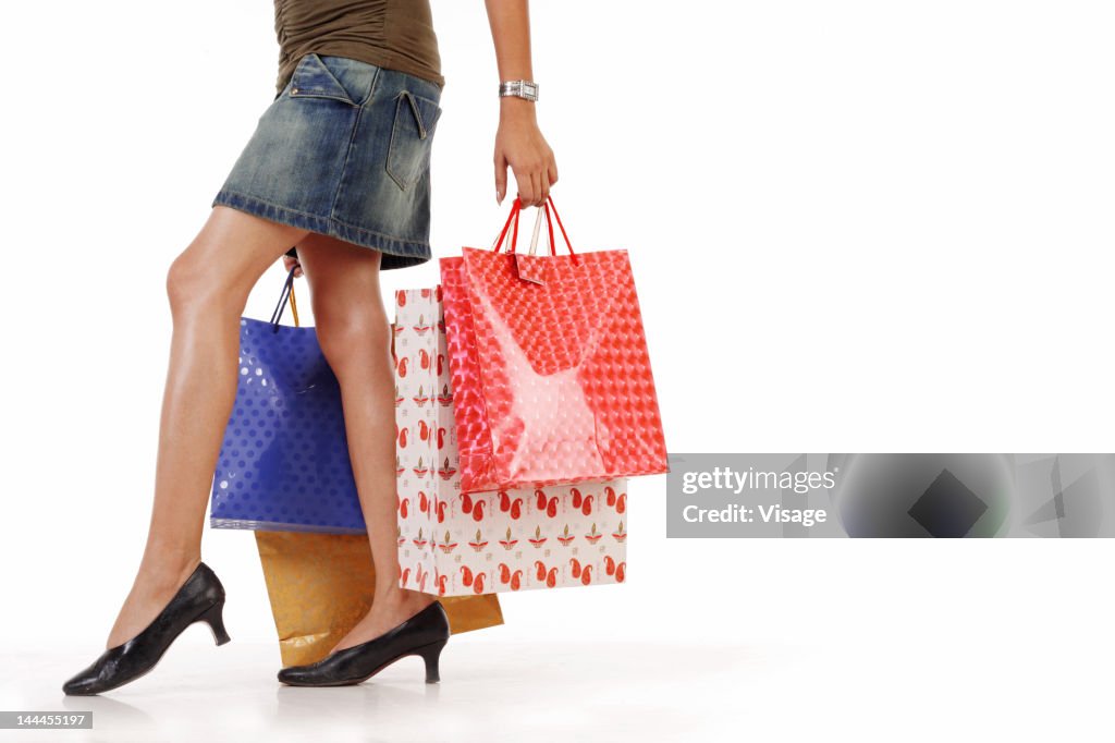 Young woman holding shopping bags, low section