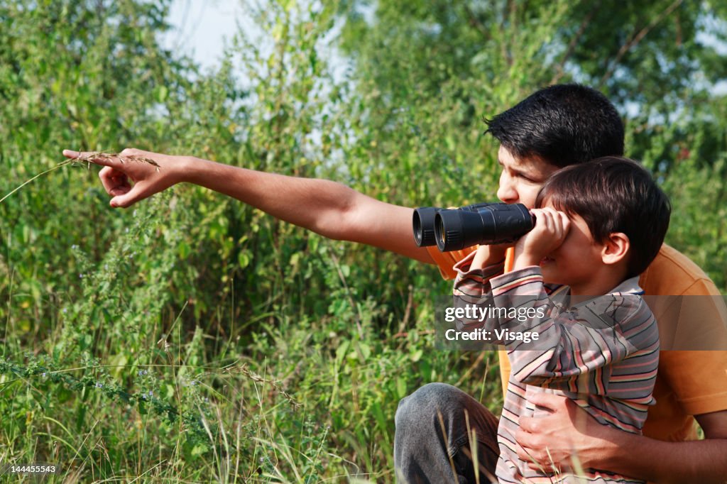 Father pointing, boy looking through binoculars