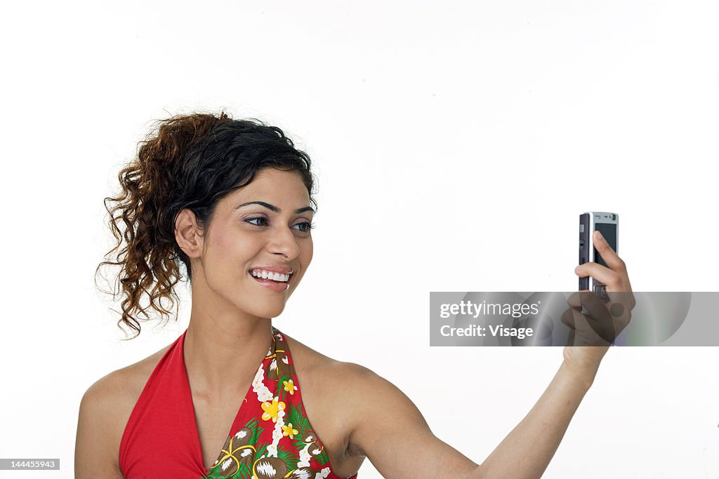 Young woman clicking her own picture using mobile phone