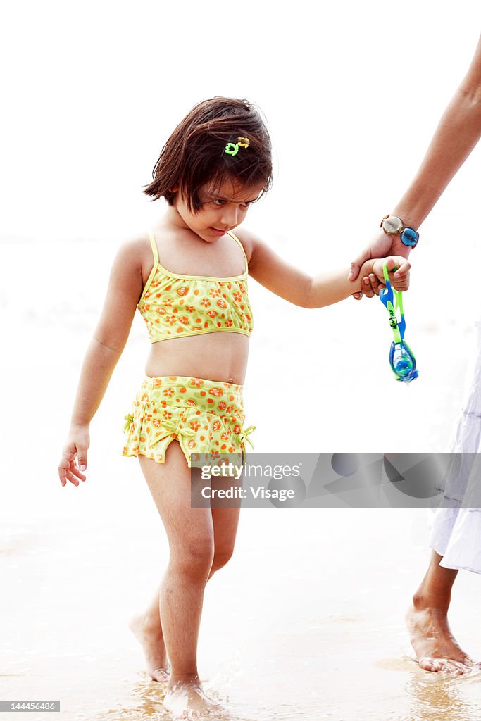 Woman holding a baby girls hand walking at a beachside