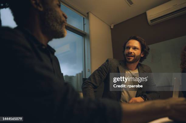 compañeros de trabajo hablando en la mesa - trabalho comercial fotografías e imágenes de stock