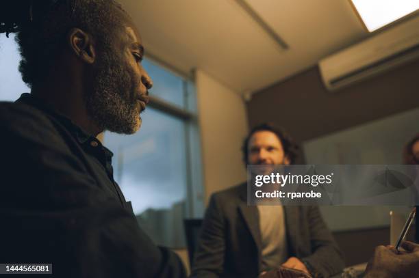 compañeros de trabajo hablando en la mesa - trabalho comercial fotografías e imágenes de stock