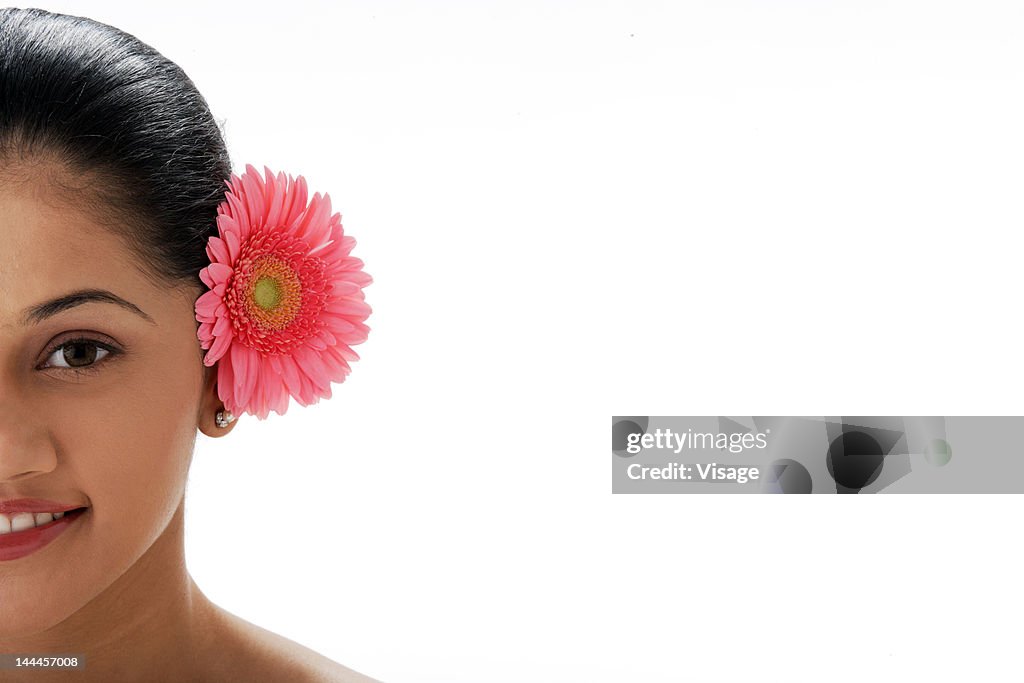 Portrait of a young woman with a gerbera flower in ear