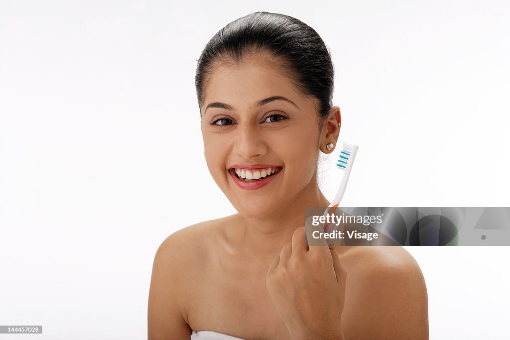 Young woman holding toothbrsh and smiling