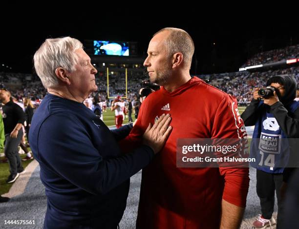 Head coach Mack Brown of the North Carolina Tar Heels and head coach Dave Doeren of the North Carolina State Wolfpack talk at midfield after their...