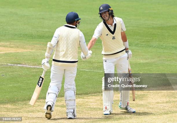 Sam Elliott of Victoria is congratulated by Jon Holland after reaching 50 runs during the Sheffield Shield match between Victoria and Tasmania at...