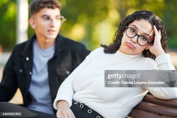 bored woman looking at camera while on a date in the park. - menschliche beziehung stock-fotos und bilder