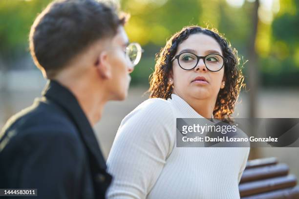 woman keeping distance and rejecting a man while having a date together in a park. - first date stockfoto's en -beelden