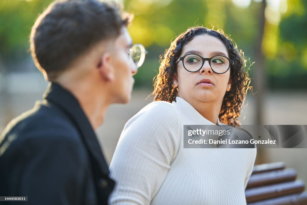 Woman keeping distance and rejecting a man while having a date together in a park.