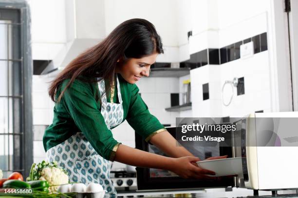 a young woman using a oven - mikrowelle stock-fotos und bilder