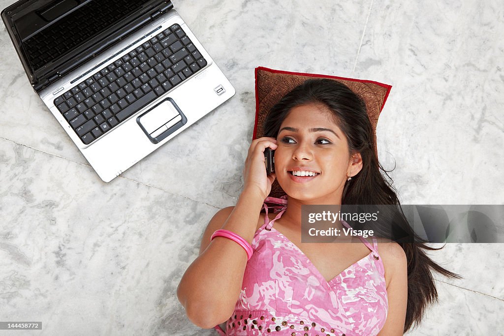 Woman lying down on the floor and speaking on mobile phone