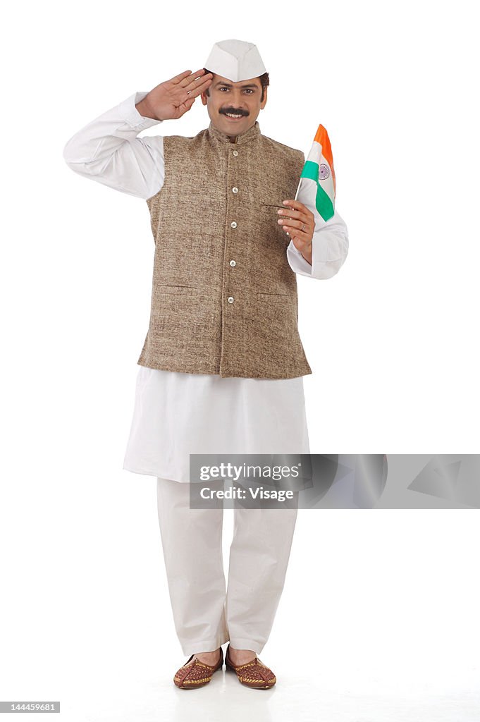 Man traditionally dressed holding the Indian flag and saluting