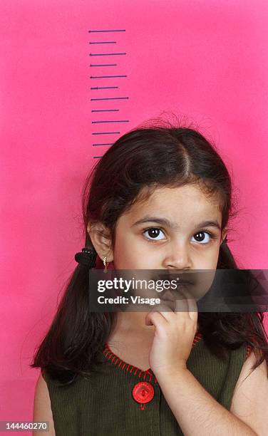 girl standing at height chart - growth chart stock pictures, royalty-free photos & images