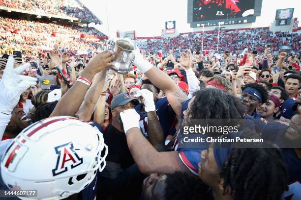 The Arizona Wildcats celebrate with the Territorial Cup after defeating the Arizona State Sun Devils 38-35 in NCAAF game at Arizona Stadium on...