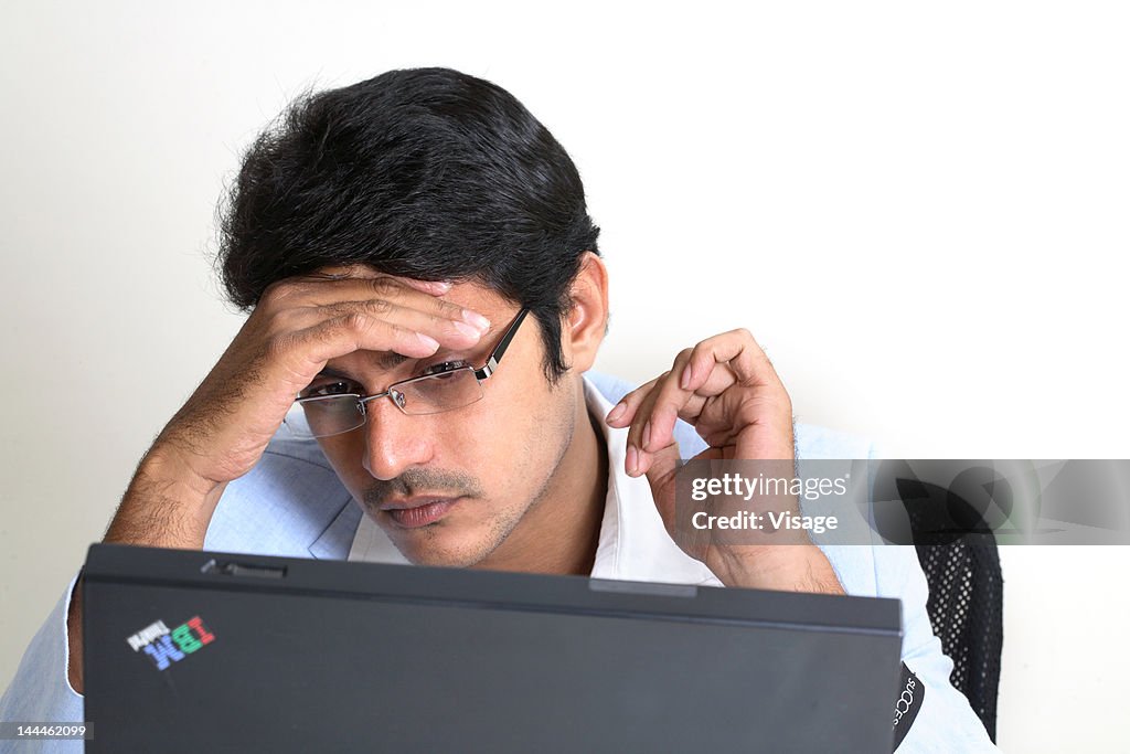 A man looking into his laptop, thinking